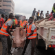 Rescue workers carry the remains of a person onto the back of a truck.